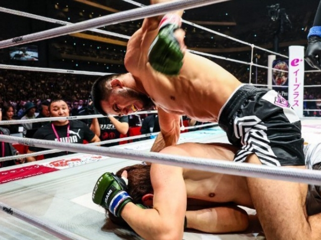 朝倉がシェイドゥラエフのファウンディングに顔を包んで避けている。  /写真=RIZIN公式SNS