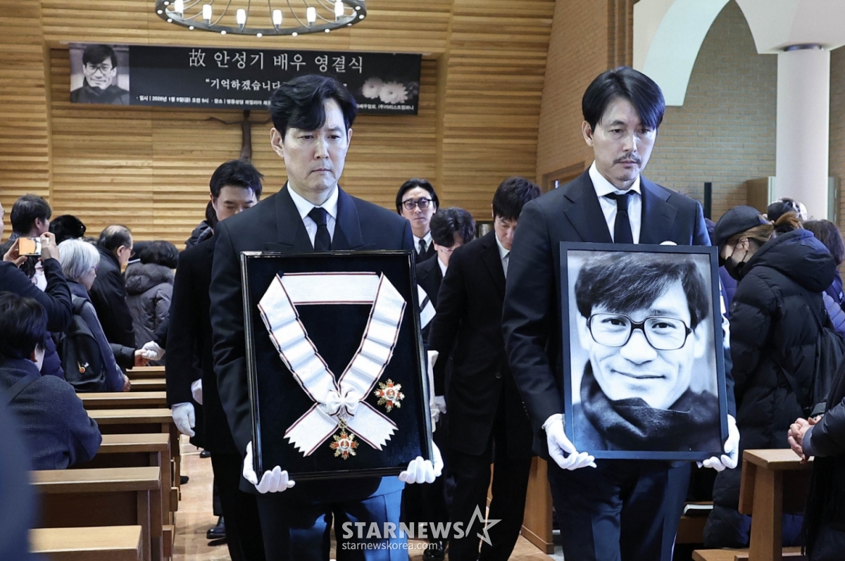Actors Lee Jung-jae and Jung Woo-sung hold the portrait and medal of the deceased at the funeral ceremony of the late Ahn Sung-ki at Myeongdong Cathedral in Jung-gu, Seoul on the morning of the 9th./2026.01.09 / Photo = Kim Hwi-seon hwijpg@