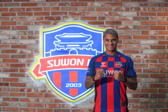 图为德兰在水原FC标志前摆出造型。 =照片=水原FC提供。