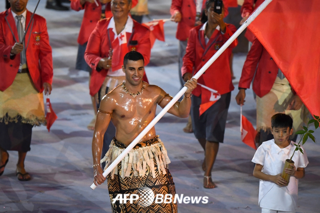  Фита Таупатопуа (справа) 'Мускульный человек Тонга' была знаменосцем на церемонии открытия Олимпийских игр 2018 года в Пхенчхане. /AFPBBNews =Новости 1