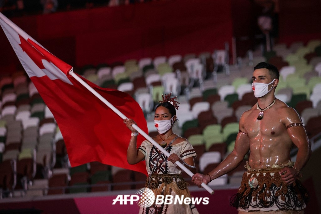  Человек-мышечник "Тонга" Пита Таупатопуа (справа) был знаменосцем во время церемонии открытия Олимпийских игр 2020 года в Токио. /AFPBBNews =Новости 1