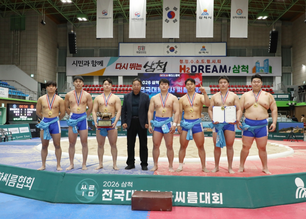 Университет Донг-А (город Пусан), выигравший командный турнир среди колледжей 2026 года в гимназии Самчхока в Самчхоке, провинция Канвон, делает памятное фото Ким Вон-ха (четвертое слева) в честь председателя Ассоциации Самчхока. /Фото = Предоставлено Корейской ассоциацией реслинга.