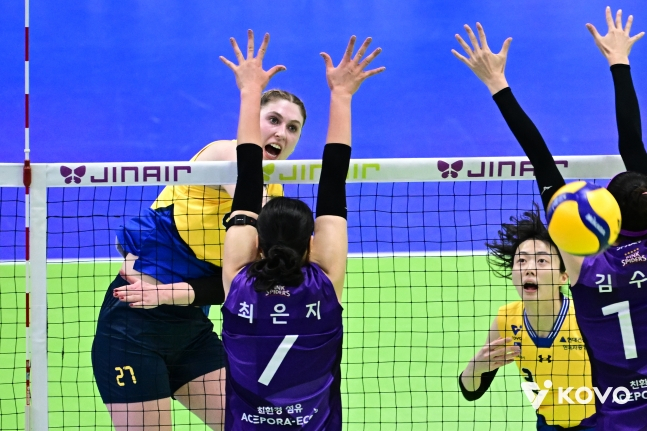 Hyundai Engineering &amp; Construction's Kari (left) is pushing a strong attack between Heungkuk Life's double blockers. /Photo = Courtesy of KOVO