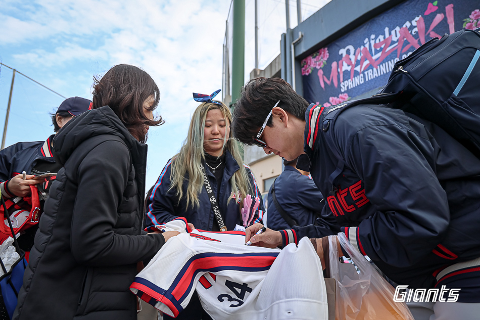 Lotte Giants closer Kim Won-joong (right) is signing autographs for fans. /Photo = Courtesy of Lotte Giants