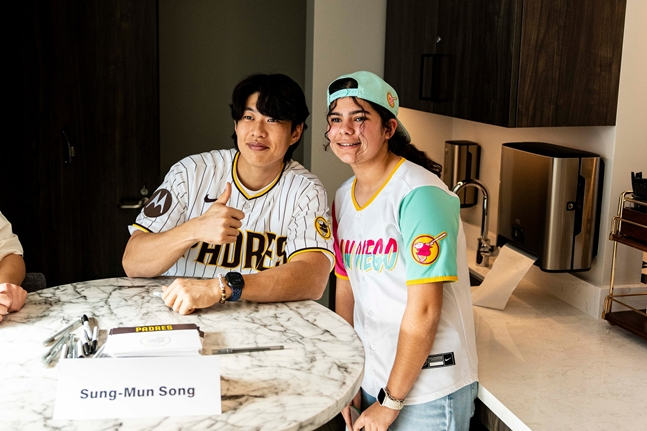 与当地球迷合影的宋成文（左）。 =照片=圣地亚哥教士队官方SNS。