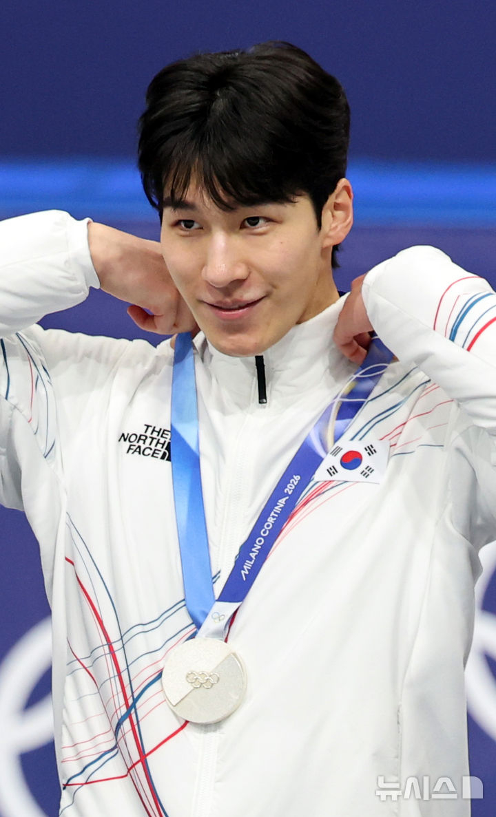 Hwang Dae-heon, who won the silver medal in the men's 1,500m short track final at the 2026 Milan-Cortina D'Ampezzo Winter Olympics, is touching the medal on the 14th (local time). /Photo = Newsis