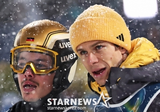 フィリップ·ライムント（左）が2026年ミラノ·コルティナダンペッツォ冬季五輪スキージャンプ男子スーパーチーム決戦中、競技場を眺めている。 /ロイター=ニュース1