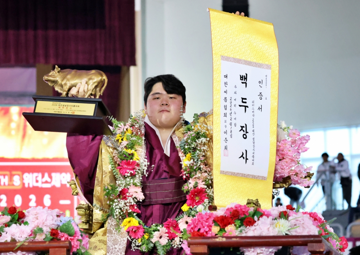 Kim Min-jae (Yeongam-gun Folk Ssireum Team), who was crowned Baekdu Jangsa (140kg or less) at Withers Pharmaceutical 2026 Taean Lunar New Year Ssireum Competition held at Taean Indoor Gymnasium in Taean-gun, Chungcheongnam-do, is taking a commemorative photo with a business certificate and a bull trophy on a funeral sedan. /Photo = Courtesy of the Korea Wrestling Association