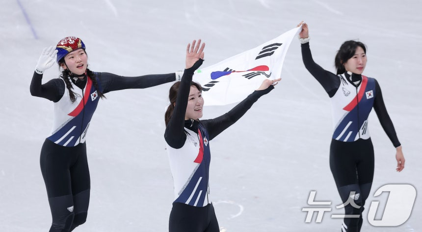 图为5月18日（当地时间），韩国女子短道速滑代表队的沈锡希（左起）、卢道熙（音）和李素妍（音）在意大利米兰冰上滑冰馆举行的2026米兰·科尔蒂纳丹佩佐冬奥会短道速滑女子3000米接力决赛中获得金牌后，正围着太极旗向观众席致意。 =照片=news1