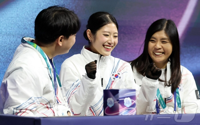 图为李海仁（中）在"Kiss &amp; Cry Zone"确认分数后，正和教练组一起开心地笑着。 =照片=news1