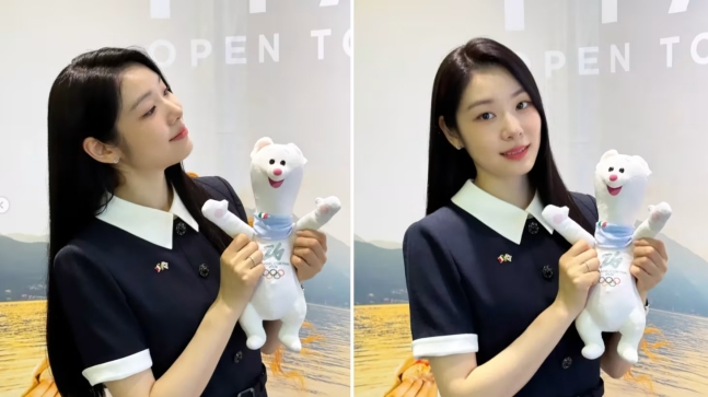 图为金妍儿正拿着2026米兰·科尔蒂纳丹佩佐冬奥会吉祥物蒂娜玩偶合影留念。 =图为，2026米兰-科尔蒂纳丹佩佐冬奥会官网。
