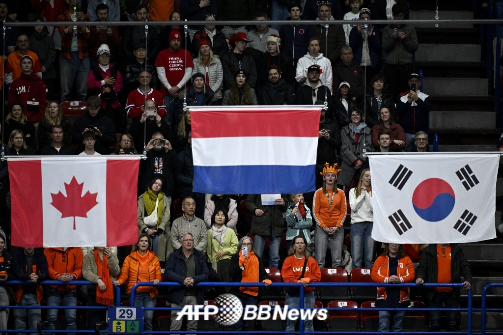 女子短道速滑国家队队员金吉利在2026米兰奥运会短道速滑1000米项目中摘得铜牌，随后颁奖仪式上"不良"太极旗(右)升起。 =法新社BBNews=新闻1。