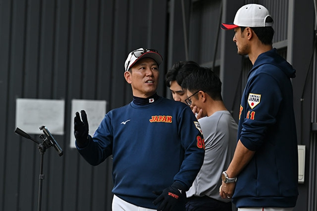 图为，日本队主教练饭田博一（中）和达比修有（右）教练正在交谈。 =日本棒球代表队官方网站。