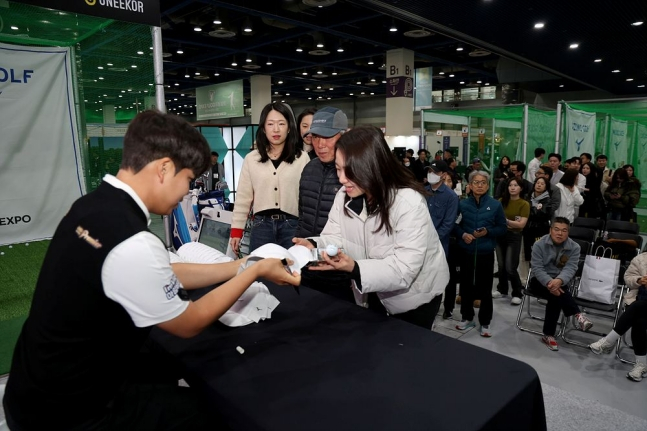 Jang Yoo-bin (left) delivers a signed hat to fans at the "2026 Mail Business Golf Expo" on the 21st.  /Photo = Courtesy of KPGA