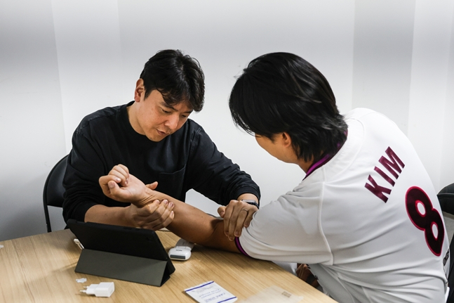图为正在观察左腕投手金成民（右）胳膊肘的金成俊医生。 =照片:kiwoom heroes。