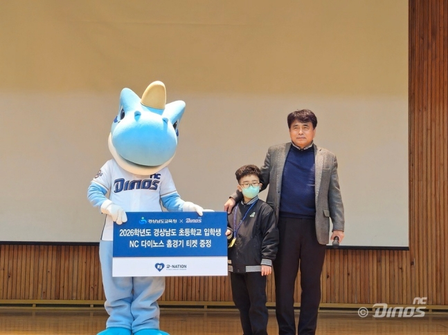 NC Dinos吉祥物丹迪（左）3日来到道内良德小学，向参加入学仪式的学生们表示祝贺，并提供了主场比赛门票。 =照片:NC Dinos提供。