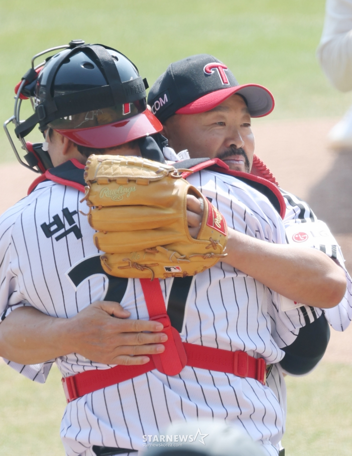 2026新韓（シンハン）SOLBankKBOリーグ公式開幕戦「LGツインズ対KTウィズ」の試合が先月28日、ソウル蚕室（チャムシル）野球場で行われた。  LGのキム·ヨンイルトレーニングコーチがktのキム·ヒョンスを相手にLG勝利祈願の始球式をした後、捕手のパク·ドンウォンと抱擁している。 /写真=キム·ジンギョン待機者