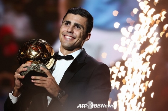 Родри ярко улыбается, поднимая трофей на церемонии награждения 2024 Ballon d'Or. /AFPBBNews =Новости 1