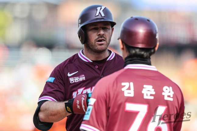 图为布鲁克斯（左）击出安打后，将装备交给金 김준完教练。 =照片=kiwoom heroes提供。