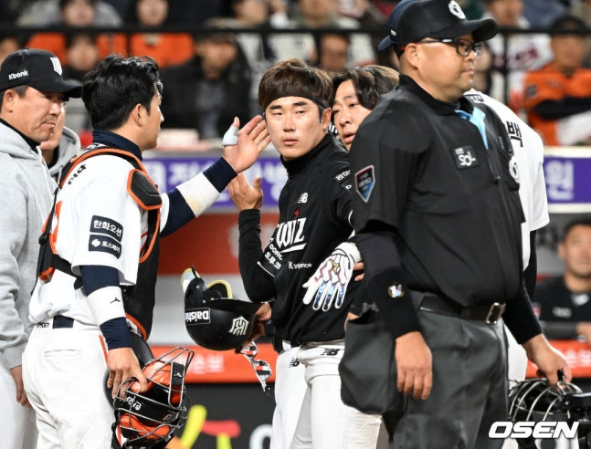 KTのホ·ギョンミン（中央）が3月31日、ハンファ戦でヘルメットをかぶった後、立ち上がり、相手投手のオム·サンベク（一番右）の腕を叩いている。 /写真=OSEN