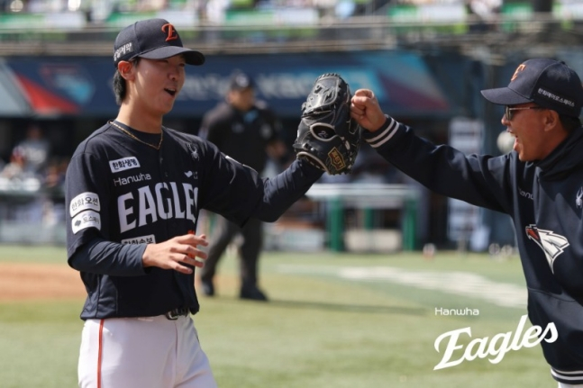 5日，韩华鹰队的黄俊书（左）在首尔市松坡区蚕室球场与斗山熊队进行的2026新韩SOL KBO联赛客场比赛中首发出场，以无失分的成绩结束局数，正以灿烂的微笑走向球员席。 =韩华鹰队。