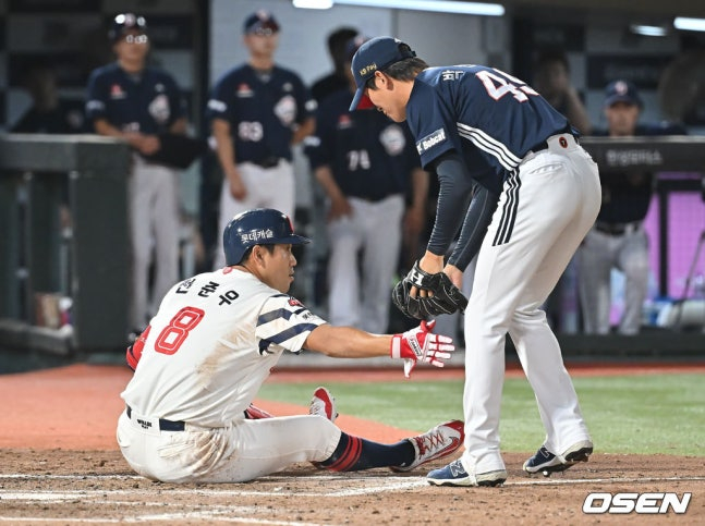 图为乐天队的全俊宇（左）在被球击中身体后，正在接受斗山队投手朴信智的道歉。  =照片=OSEN 