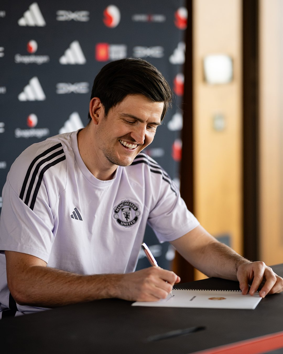 Harry Maguire smiles as he signs Manchester United re-signs. /Photo = Manchester United Official Social Network Service (SNS)