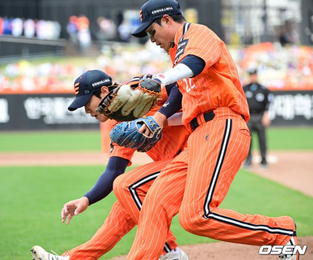 Чэ Ын Сон (справа) и Ли Сан Гю вместе бегут, чтобы поймать мяч, который прошел после ошибки, чтобы предотвратить гол третьего бегуна.