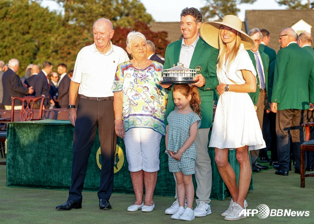 Макилрой (зеленая куртка) снимает памятную фотографию со своей семьей, которая приехала на место происшествия после двух поражений подряд. /AFPBBNews =Новости 1