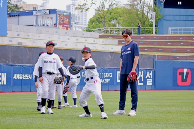 NC Dinos队的朴珉宇(右)13日在"敲击梦想"活动中正在观看棒球希望之星们的训练。 =图为，职业棒球选手协会提供。