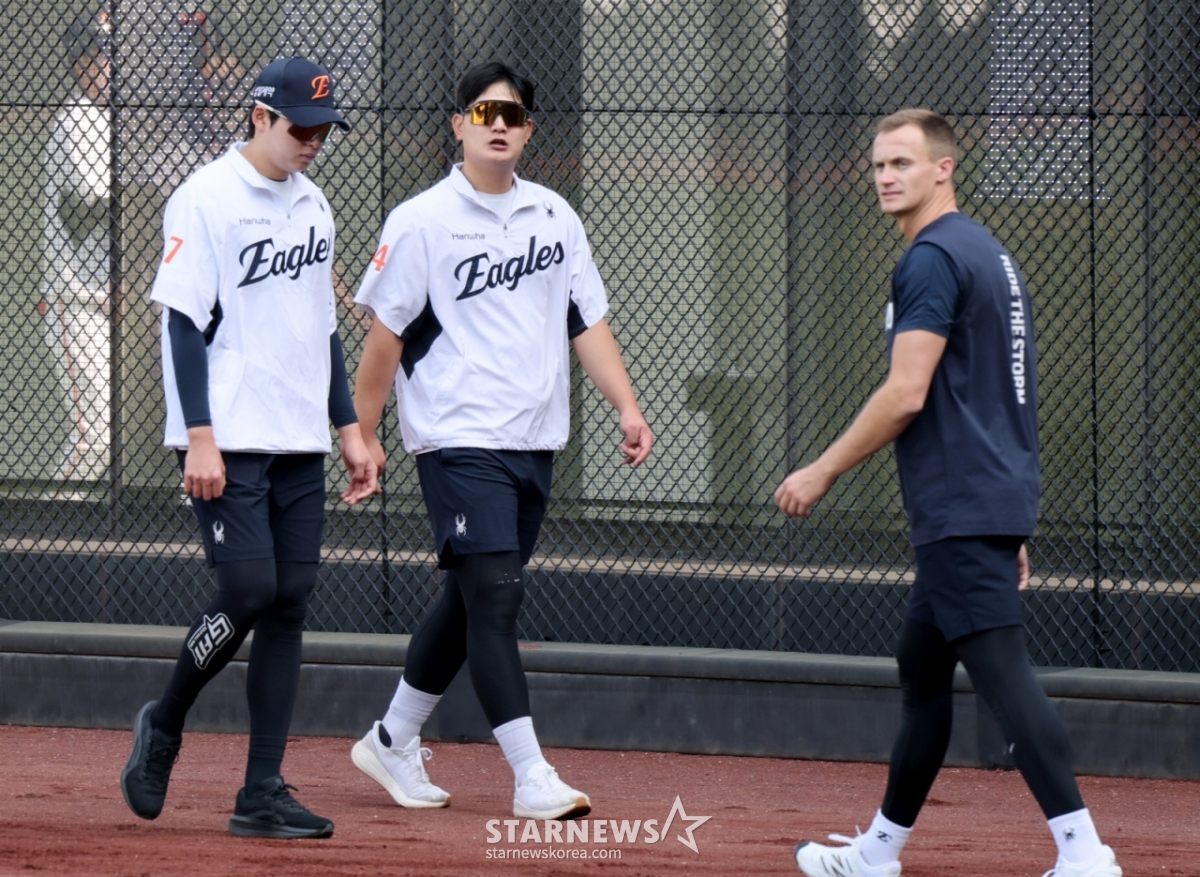 15日，在大田韩华生命球场举行的2026新韩SOL KBO联赛三星狮子队比赛前夕，韩华队的金瑞贤（中）与新担任马陆队的杰克•库欣（右）擦肩而过。 =照片=高级记者姜英祖。