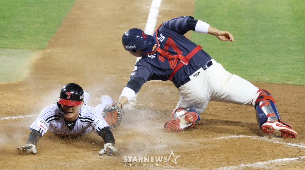 16日，2026新韩SOL KBO联赛LG双子队对乐天巨人队的比赛在首尔蚕室棒球场举行。  图为在LG队第7回合末1人出局2、3垒有人的情况下，三垒跑垒员吴志焕（音译）在朴东元的内野地滚球时跑回本垒，正在安全上垒。 乐天队的接球手是柳康男。 =照片=金镇京。