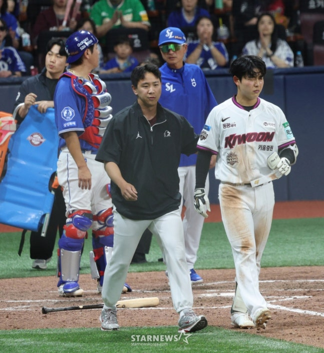 Kiwoom Heroes outfielder Park Soo-jong (right) was hit in the ear by a pitch from Yura Miyaji in the bottom of the 8th inning of the home game against Samsung Lions in the 2026 Shinhan SOL KBO League on the 27th. He remained on the ground for a while before getting up and walking toward first base. /Photo=Chief Correspondent Kim Jin-kyung