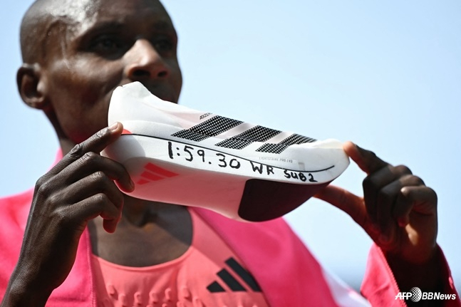 Sebastian Sawe holds up his shoes, on which he wrote the world record, after winning the 2026 London Marathon held in London, UK, on the 26th (Korean time). /AFPBBNews=NEWS1