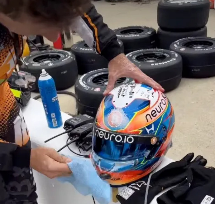  罗曼·格罗让在赛车训练中遭遇撞鸟事故后，正在擦拭自己的头盔。 =照片=《太阳报》结束。