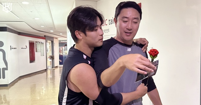 KT's Park Young-hyun (left) presents a carnation to KT first-division pitching coach Je Chun-mo on Teacher's Day ahead of the match against Suwon Hanwha on the 15th. /Photo=KT Wiz