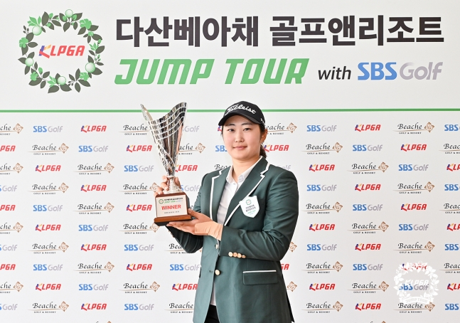 19日，金度希E在"KLPGA 2026茶山Beacha高尔夫&amp;度假村跳跃巡回赛with SBS高尔夫第5场比赛"上夺冠后，正拿着奖杯摆出造型，供记者们拍照。 =照片=KLPGA提供。