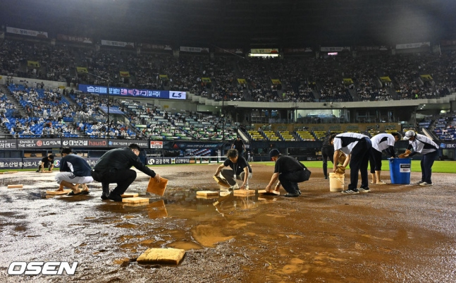 Funcionarios del club Doosan extraen el agua acumulada en el cuadro interior con esponjas. /Foto=OSEN