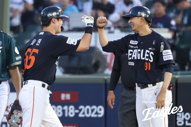 Юмин (слева) из Hanwha Eagles делает свой первый хит в дебютном матче против Lotte Giants 5-го числа и дает пять с тренером Чу Сын У. /Фото = Предоставлено Hanwha Eagles