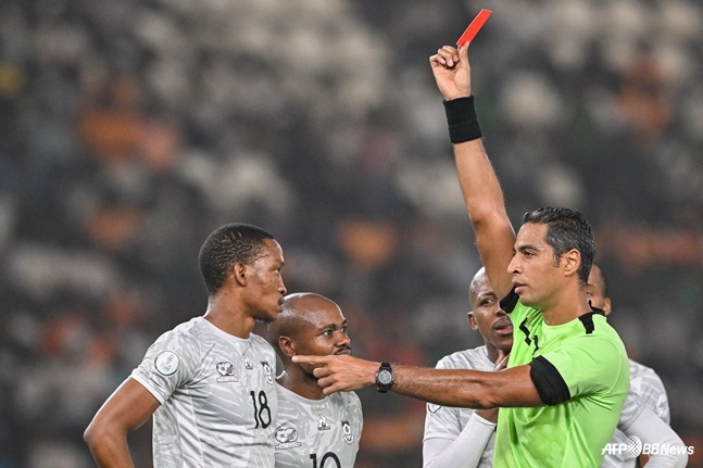Referee Amin Omar (right) holds up a red card. /AFPBBNews=NEWS1