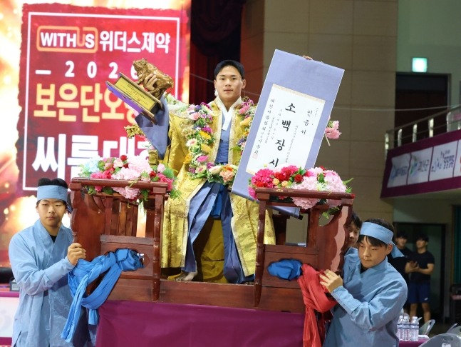 Jeon Seong-geun (center) celebrates his championship victory by riding in a flower palanquin during the Sobak Jangsa (72 kg and under) final (best of five, first to three wins) at the 'Weathers Pharmaceutical 2026 Boeun Dano Jangsa Ssireum Tournament' held on the 10th at the Boeun National Sports Center in Boeun County, North Chungcheong Province. /Photo=Korea Ssireum Association