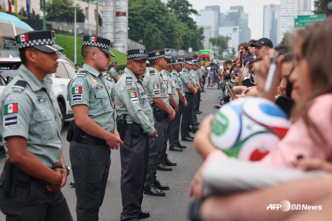 Soldados de la Guardia Nacional de México forman filas para controlar el paso entre el autobús del equipo nacional de fútbol de Inglaterra y los aficionados. /AFPBBNews=NEWS1