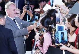 Director Christopher Nolan, smiling broadly while signing autographs [★Photo]