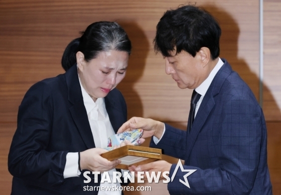 故 오요안나의 어머니 장연미씨가 15일 서울 마포구 상암동 MBC에서 진행된 유족측 기자회견에 앞서 안형준 MBC 사장으로부터 고인의 명예사원증을 받은 뒤 눈물을 흘리고 있다. /2025.10.15 /사진=이동훈 photoguy@