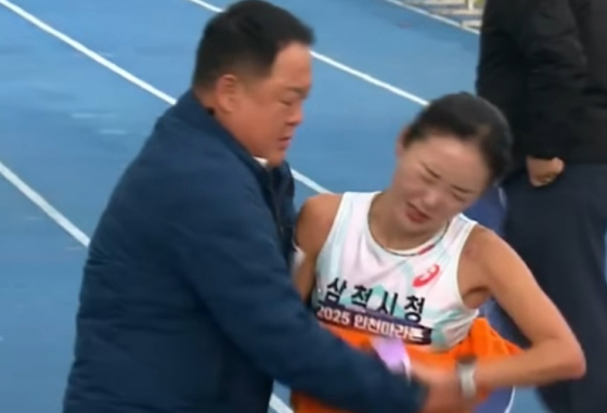 삼척시청 김완기 감독(왼쪽)이 여자 국내부 1위로 통과한 이수민을 잡아주고 있다. /사진=뉴스1 영상 갈무리