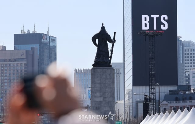 (서울=뉴스1) 김성진 기자 = 방탄소년단(BTS)의 서울 광화문광장 컴백 공연이 이틀 앞으로 다가온 19일 서울 종로구 광화문광장에서 시민들이 한 건물 외벽에 부착된 BTS 컴백 공연 광고물을 스마트폰으로 촬영하고 있다. 2026.3.19/뉴스1 Copyright © 뉴스1. All rights reserved. 무단 전재 및 재배포, AI학습 이용 금지. /사진=(서울=뉴스1) 김성진 기자