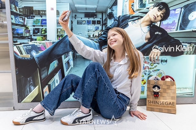 외국인 모델이 신세계면세점 명동점에서 BTS 콘텐츠를 배경으로 기념 촬영을 하는 모습. /사진제공=신세계면세점