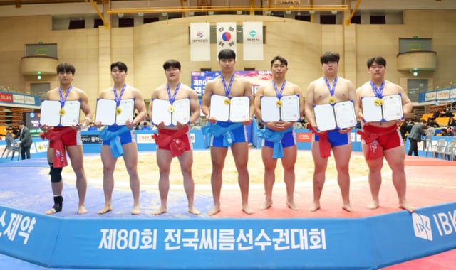 '제80회 전국씨름선수권대회' 대학교부 개인전에서 1위를 차지한 김현우(한림대학교), 이용수(울산대학교), 강준수(경기대학교), 박주환(울산대학교), 김민규(동아대학교), 전민규(영남대학교), 이혁준(인하대학교)가 메달을 메고 상장을 들고 기념사진을 찍고 있다(왼쪽부터). /사진=대한씨름협회 제공