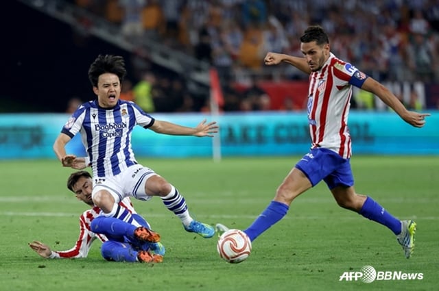 Takeshi Kubo (left) falls to the ground after a tackle by an opponent during the 2025-2026 Spanish King's Cup (Copa del Rey) final between Real Sociedad and Atletico Madrid at Estadio La Cartuja in Seville, Spain, on the 19th (Korean time). /AFPBBNews=NEWS1