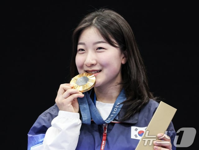 South Korea shooting team member Ban Hyo-jin is shown biting her gold medal at the 2024 Paris Olympics women's 10m air rifle podium ceremony. /Photo=NEWS1